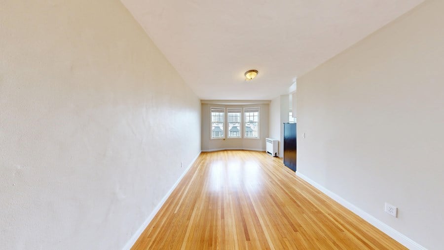 A long hallway with wooden floors and white walls.